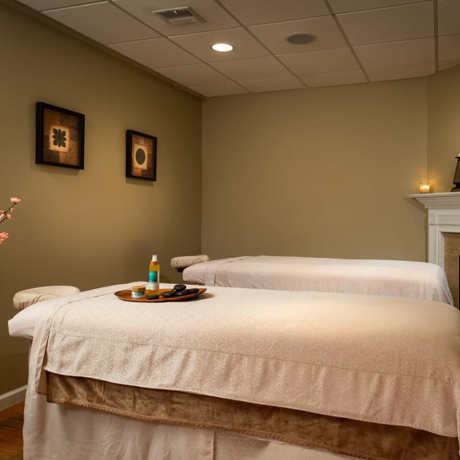 Spa room with brown walls with double spa tables with spa hot rocks and oils