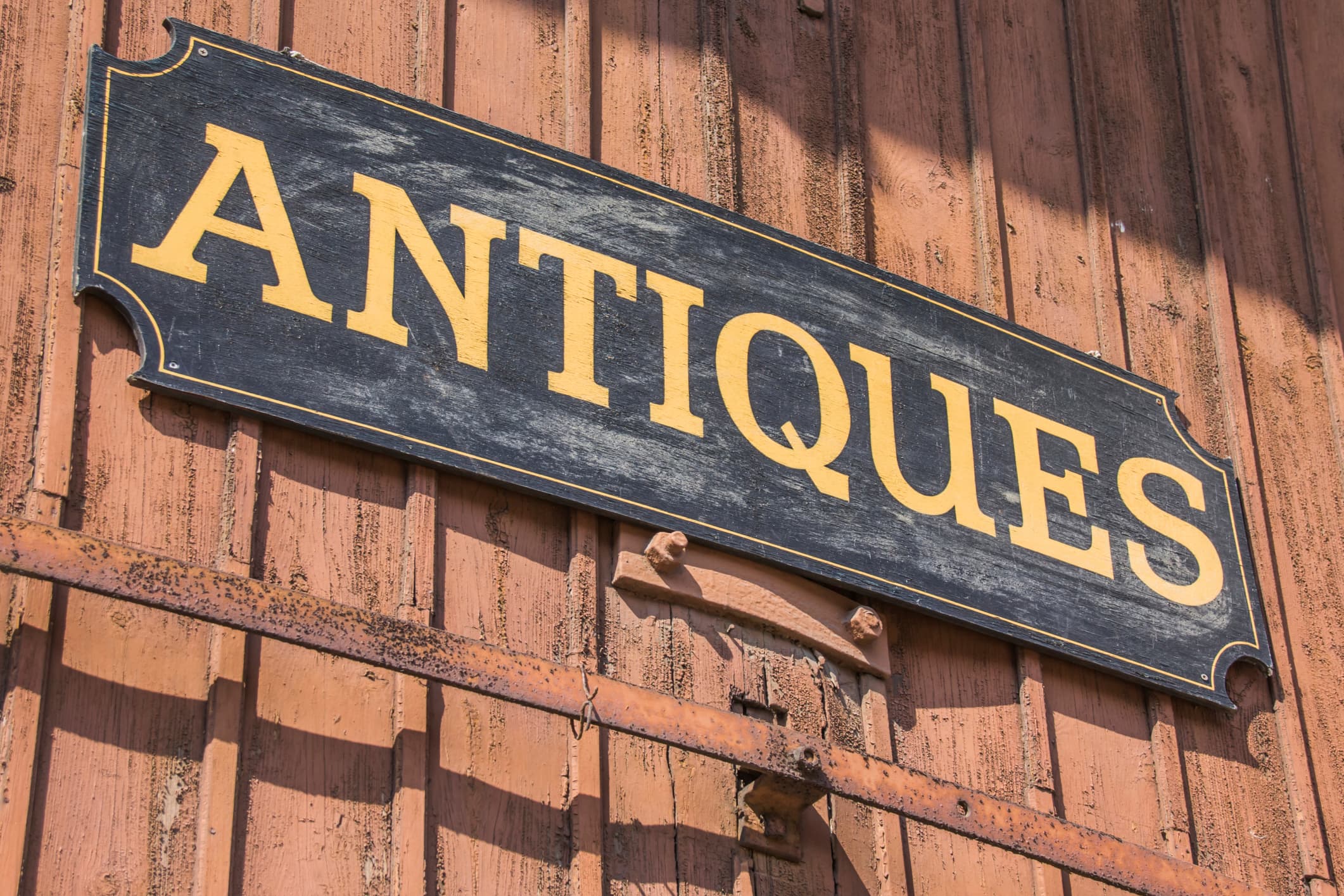 A weathered sign reading "ANTIQUE" against a rustic wooden background.