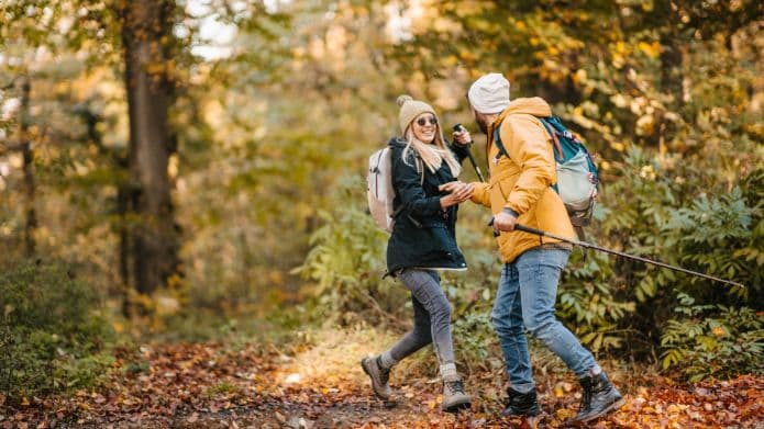Two hikers share a joyful moment on a scenic forest trail during autumn.