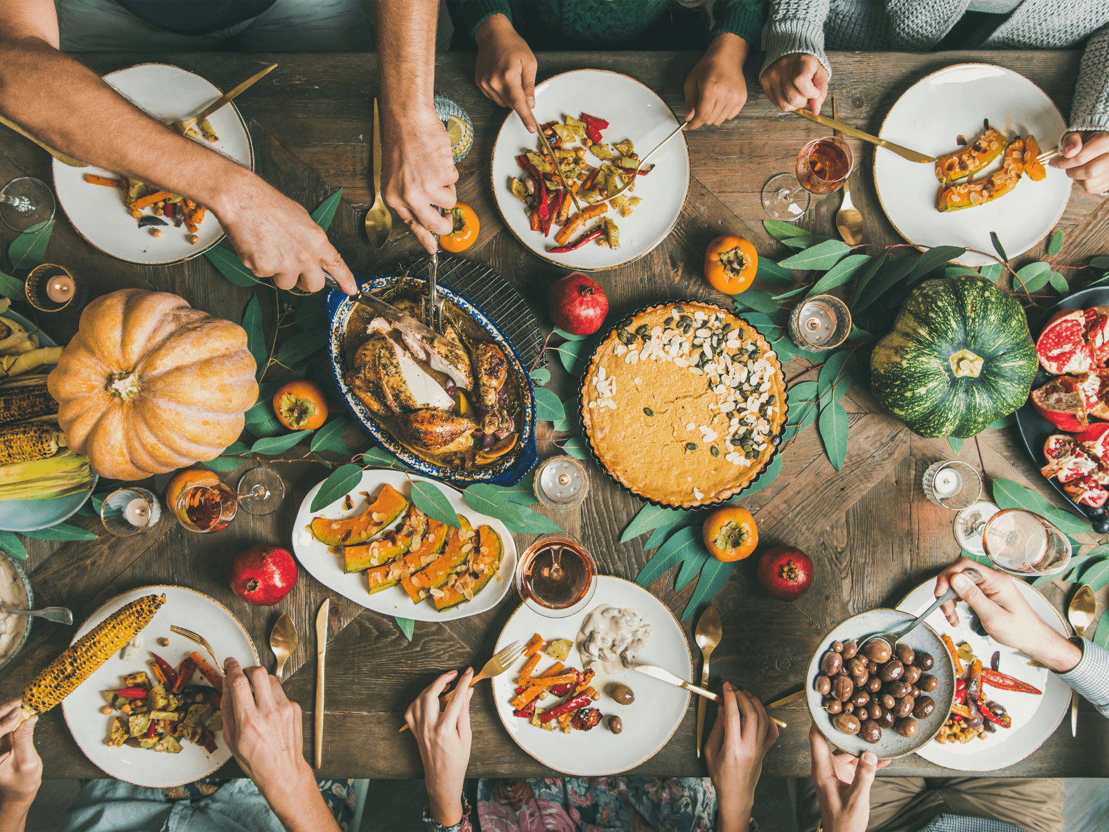 A festive table filled with autumn dishes, garnished with seasonal vegetables and surrounded by people sharing a meal.