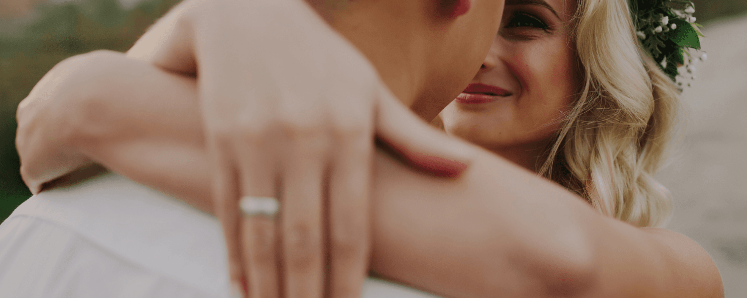 A couple shares a tender embrace, with the bride smiling at her partner.