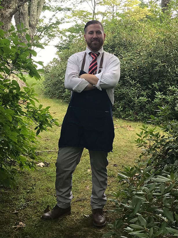 bearded chef standing in a wooded area