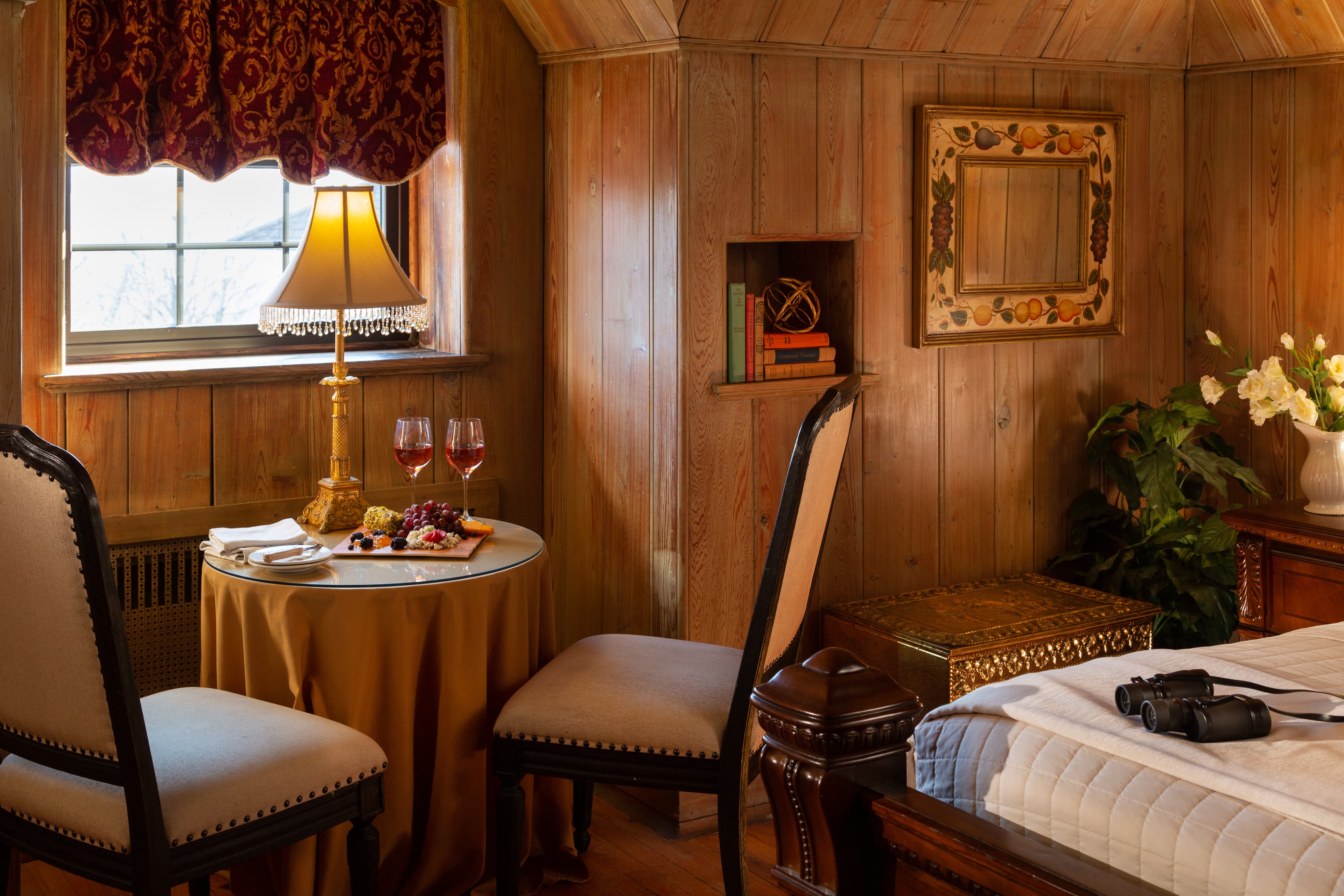 Cozy wooden room with a small dining table, two chairs, and a decorative lamp.