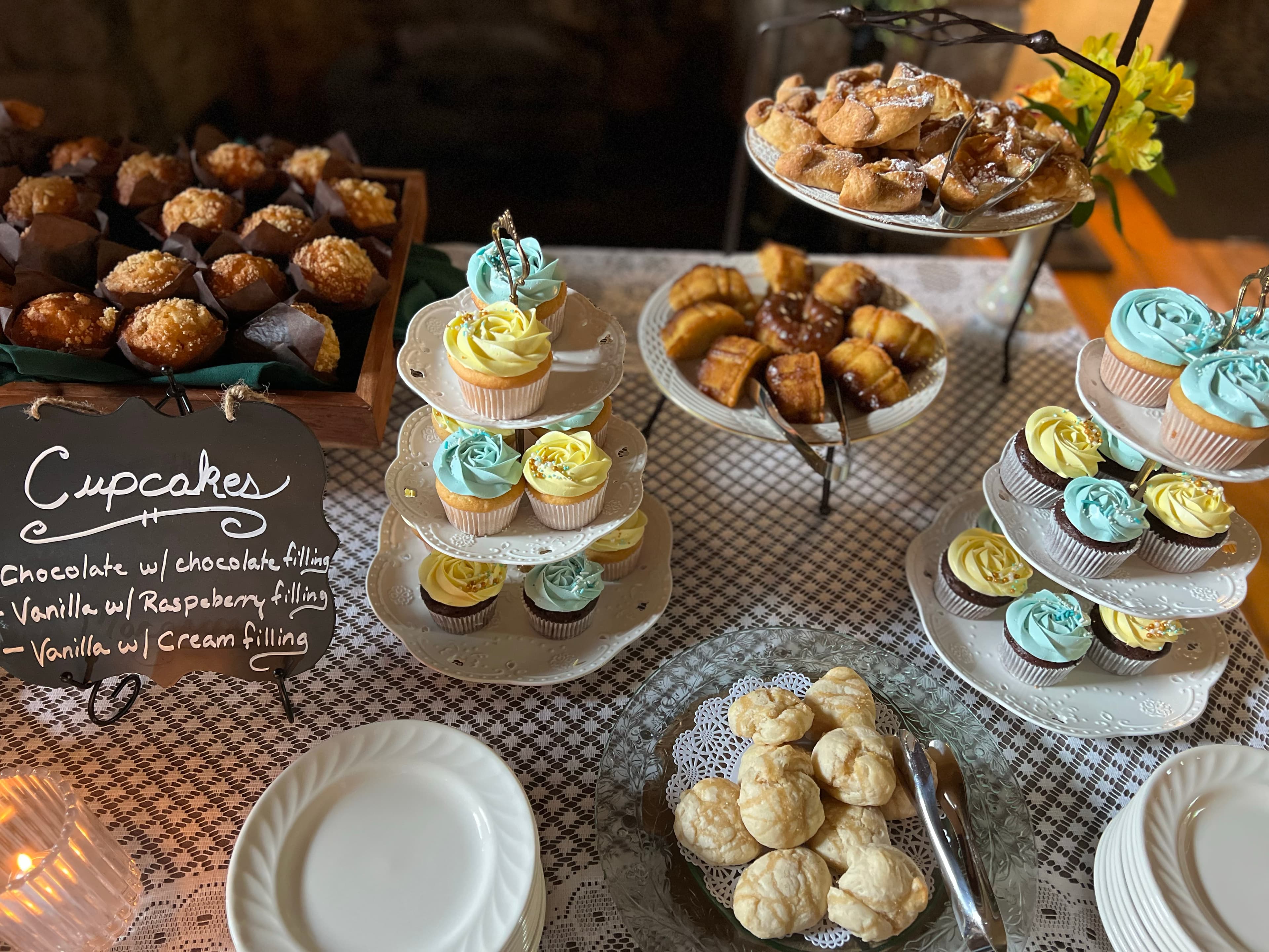 A buffet table filled with cupcakes, pastries, and other sweet treats, including muffins and croissants.