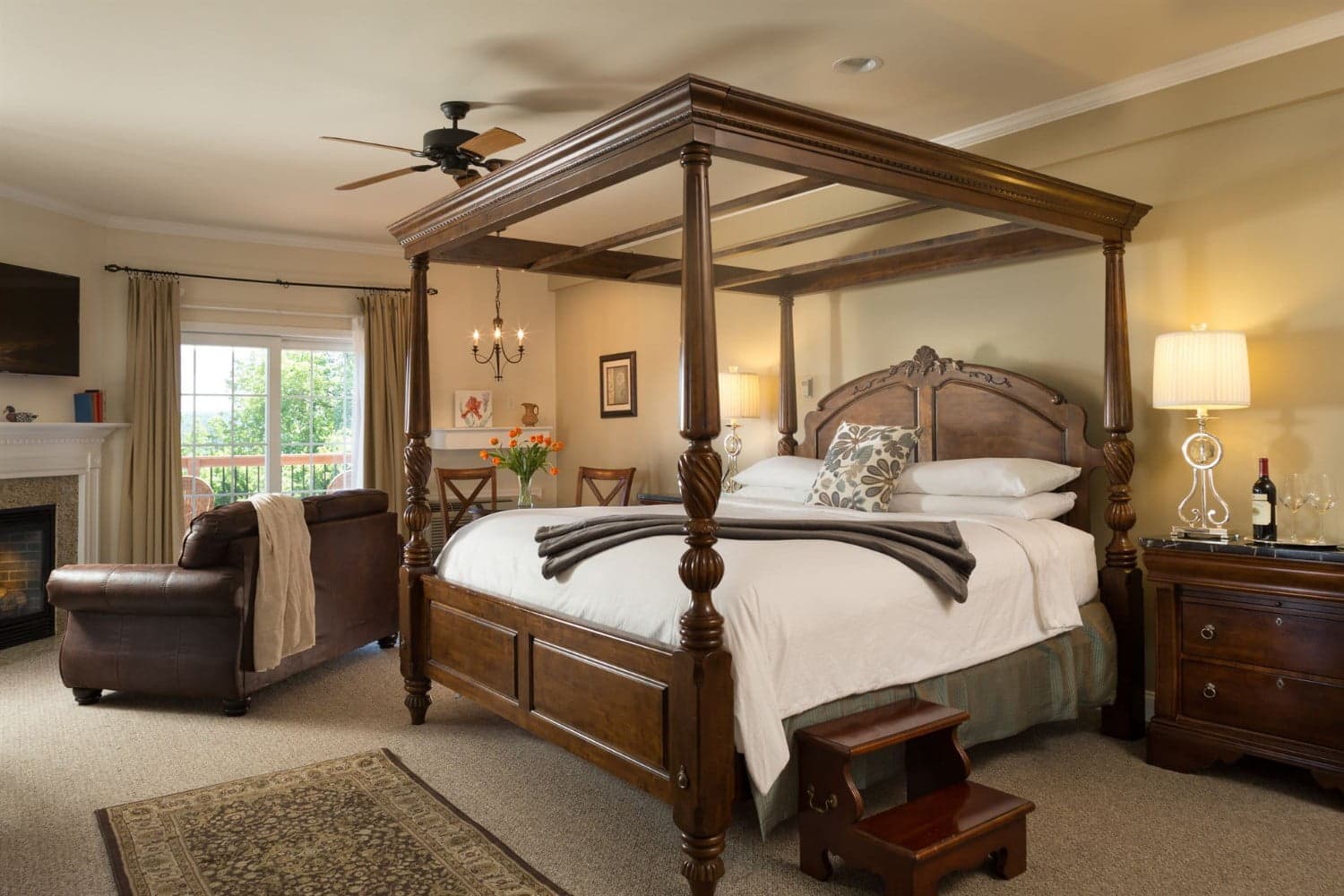A cozy bedroom featuring a four-poster bed, a plush armchair, and a view through a window.