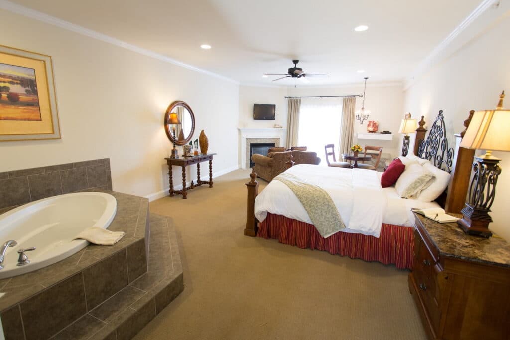 A spacious hotel room featuring a king-size bed, a jetted tub, and a cozy seating area.