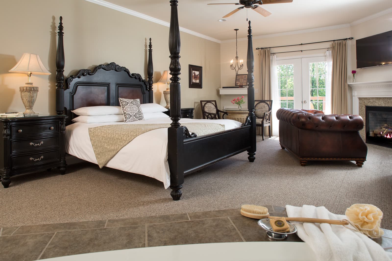 A stylish bedroom featuring a four-poster bed, cozy seating area, and large windows with natural light.