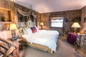 Cozy bedroom featuring a decorative wooden bed, warm lighting, and rustic wooden walls.