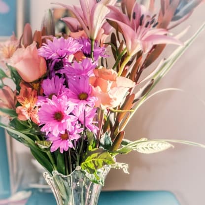 A bouquet of colorful flowers with greenery in a clear vase.