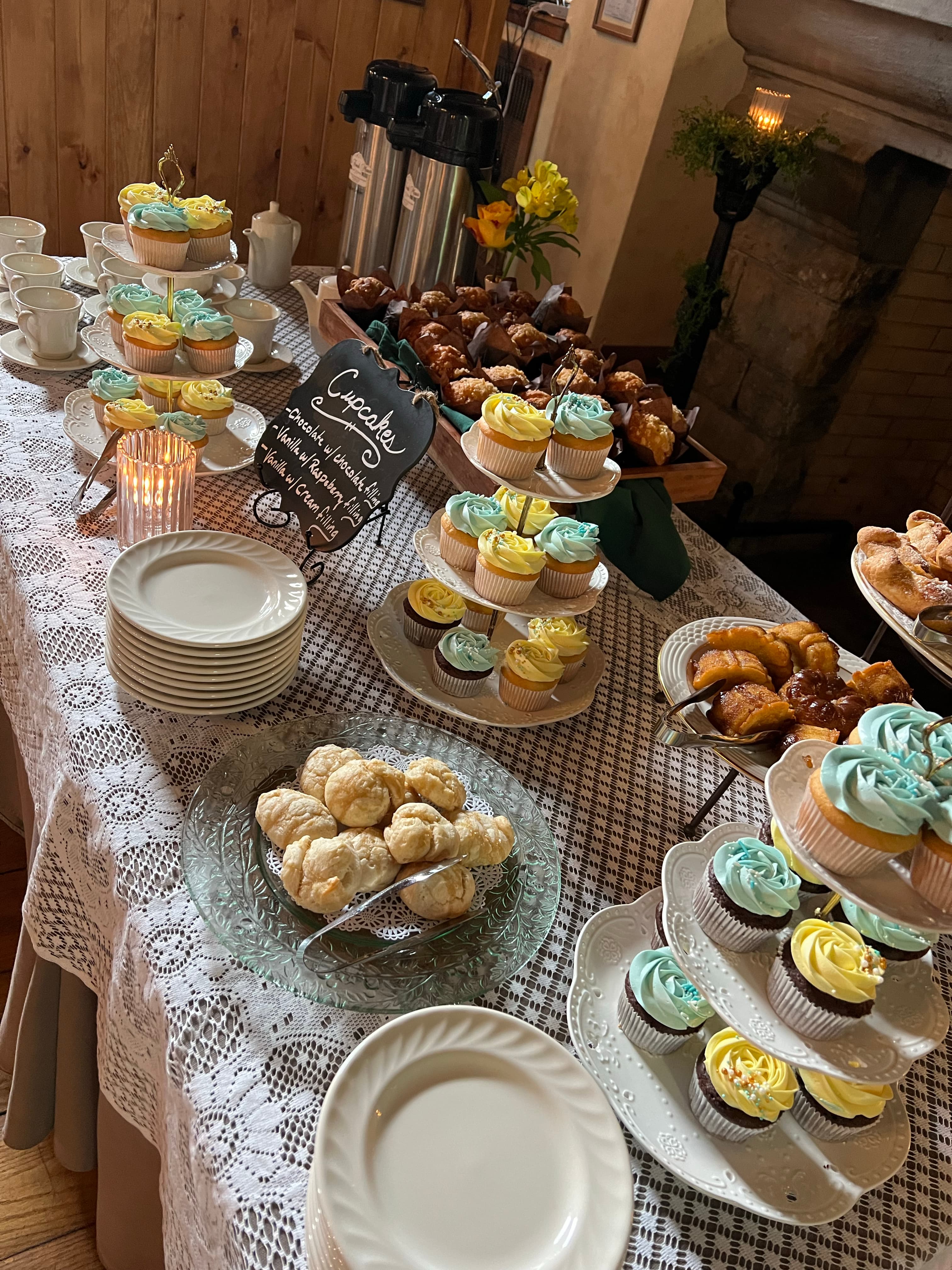A buffet table filled with cupcakes, pastries, and coffee, with a variety of flavors and decorations.