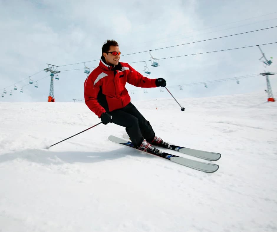A skier in a red jacket gracefully navigates a snowy slope.