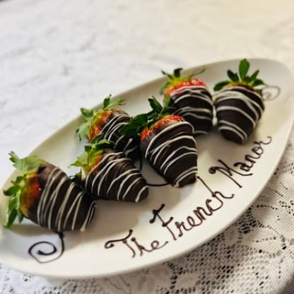 A plate of chocolate-covered strawberries with the words 'The French Manor' written in chocolate.