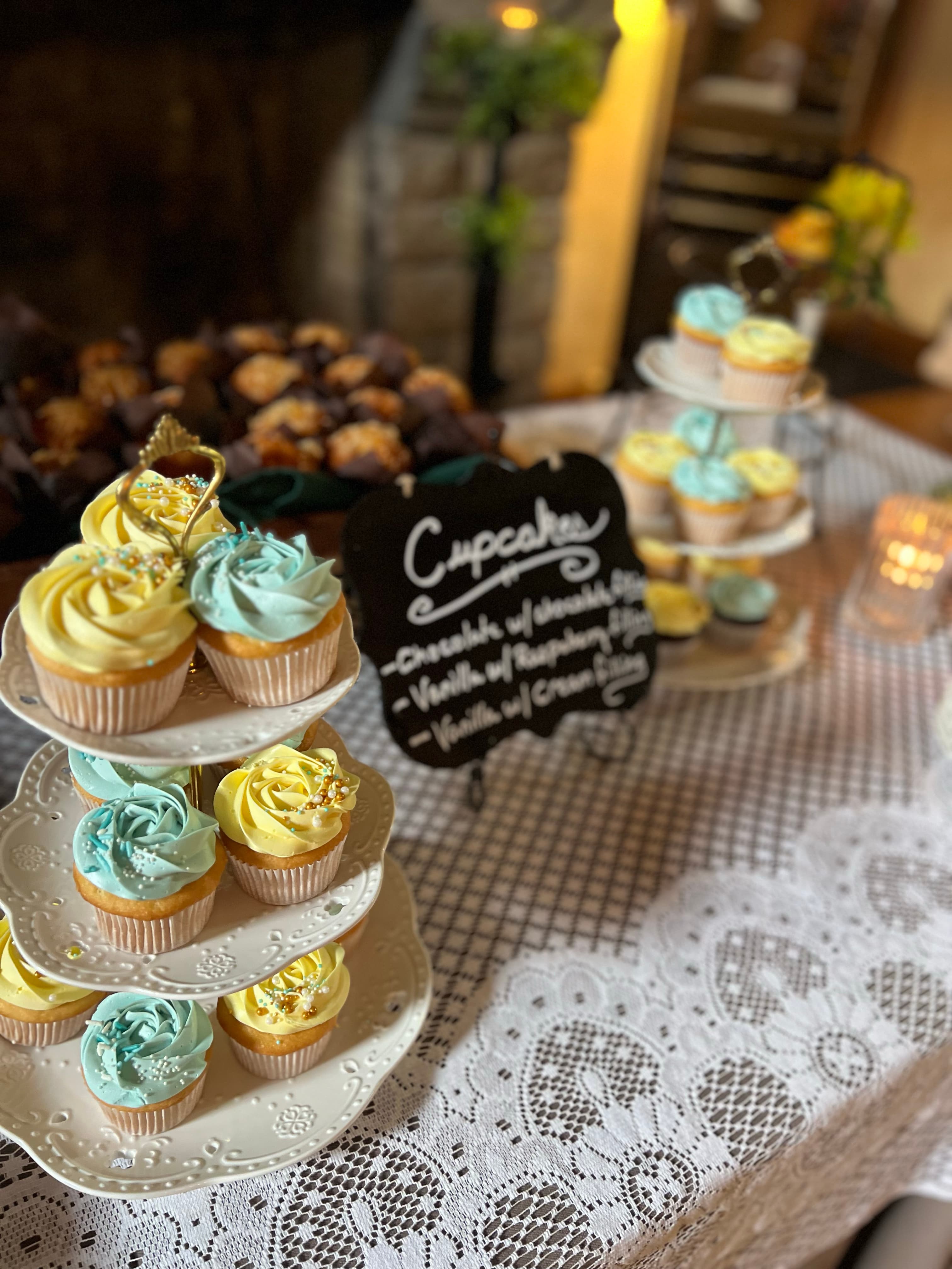 A display of cupcakes with blue and yellow frosting, arranged on a three-tiered stand.