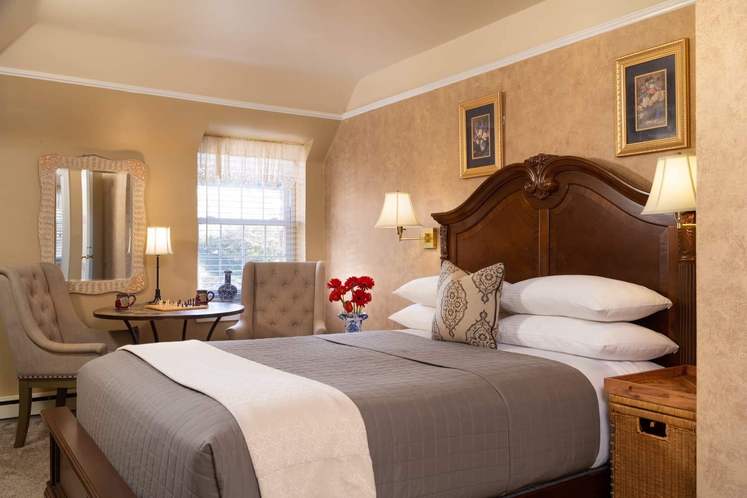 A cozy bedroom featuring a large bed, elegant decor, and a small dining table with two chairs.