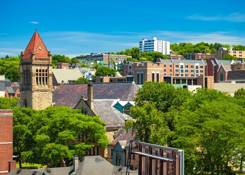 A scenic view of a city skyline featuring historic buildings and lush greenery under a clear blue sky.