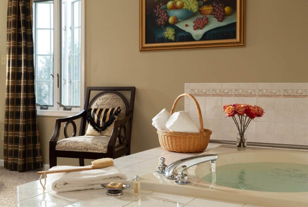 A serene bathroom featuring a tub, a chair, fresh towels, and decorative flowers.