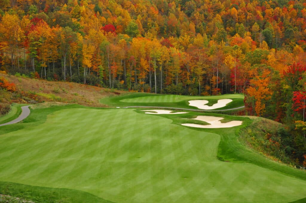 A picturesque golf course surrounded by vibrant autumn foliage.