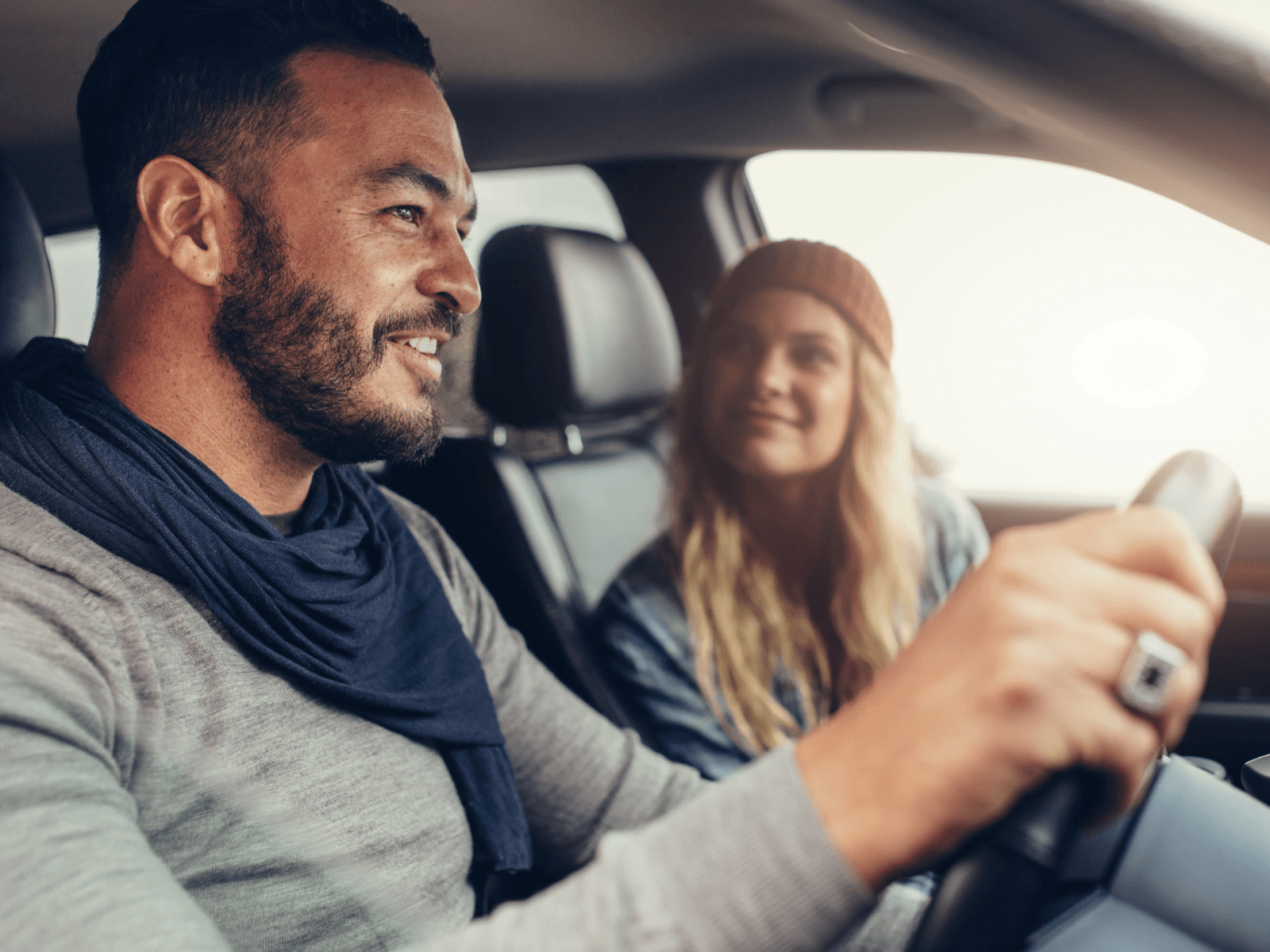 A man and a woman smile at each other while sitting in a car.