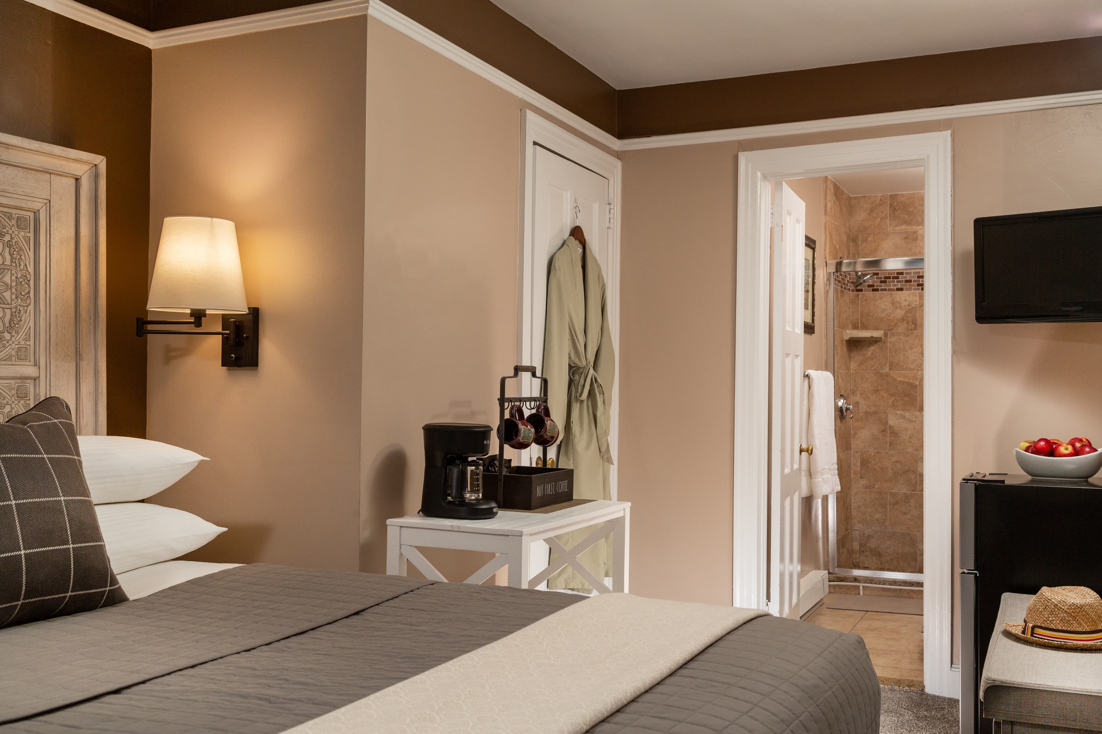 Cozy hotel room featuring a bed, lamp, coffee station, and an adjoining bathroom.