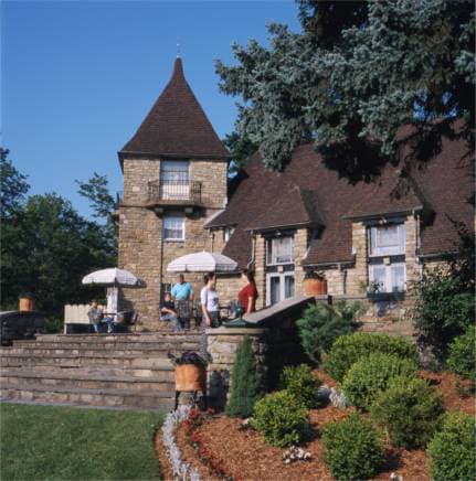 A group of people relaxing on the patio of a historic stone building.