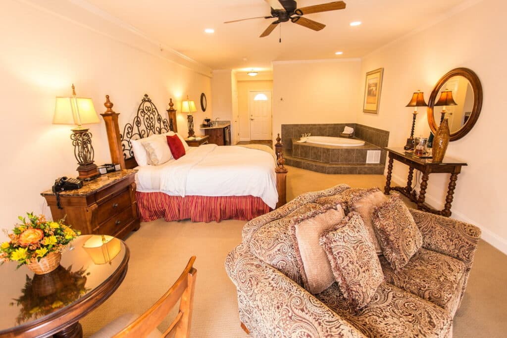 A cozy hotel room featuring a bed, a seating area, and a whirlpool tub.