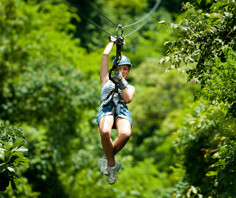 A person zip-lining through a lush green forest.