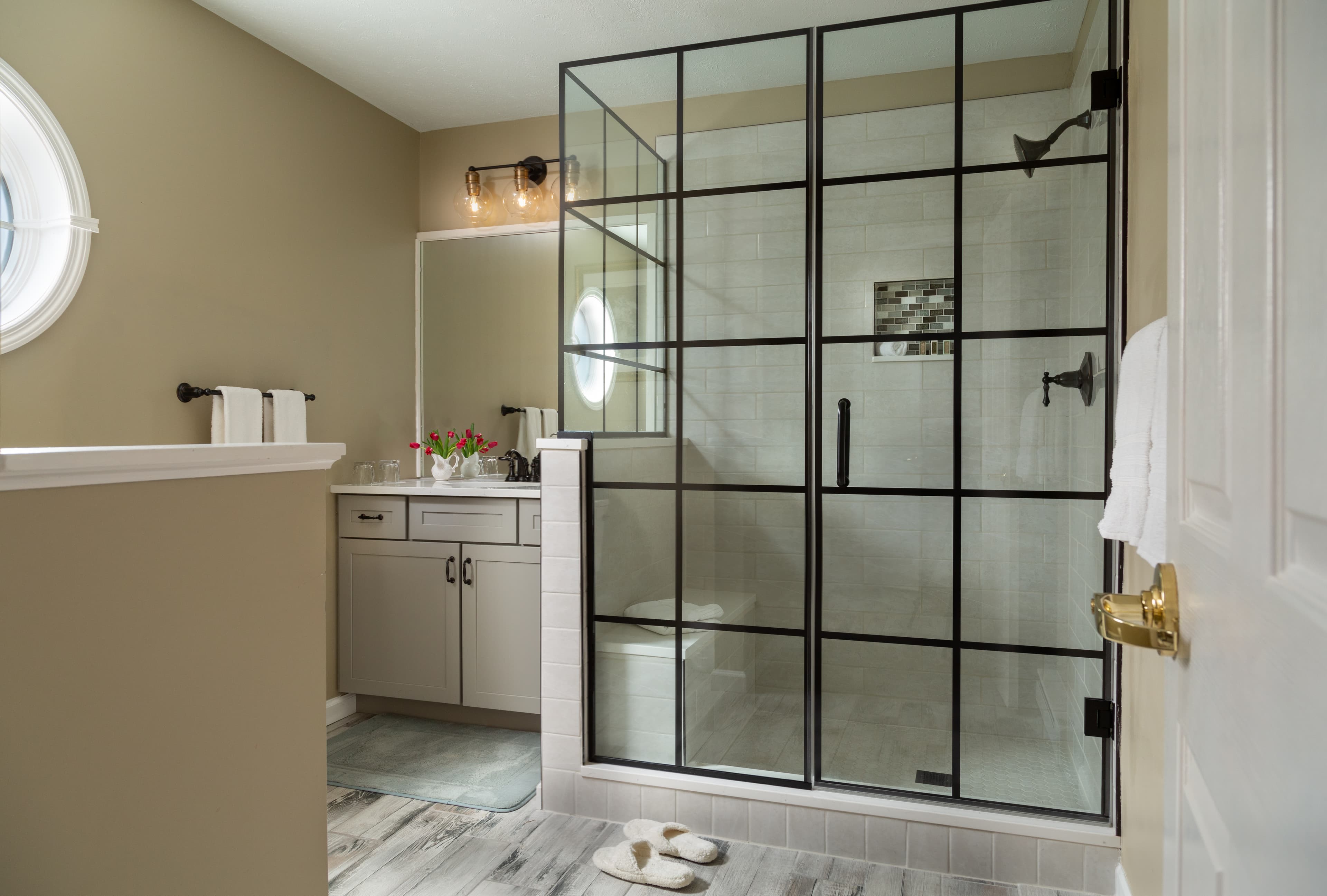 Modern bathroom featuring a glass-enclosed shower, vanity with flowers, and neutral-toned walls.