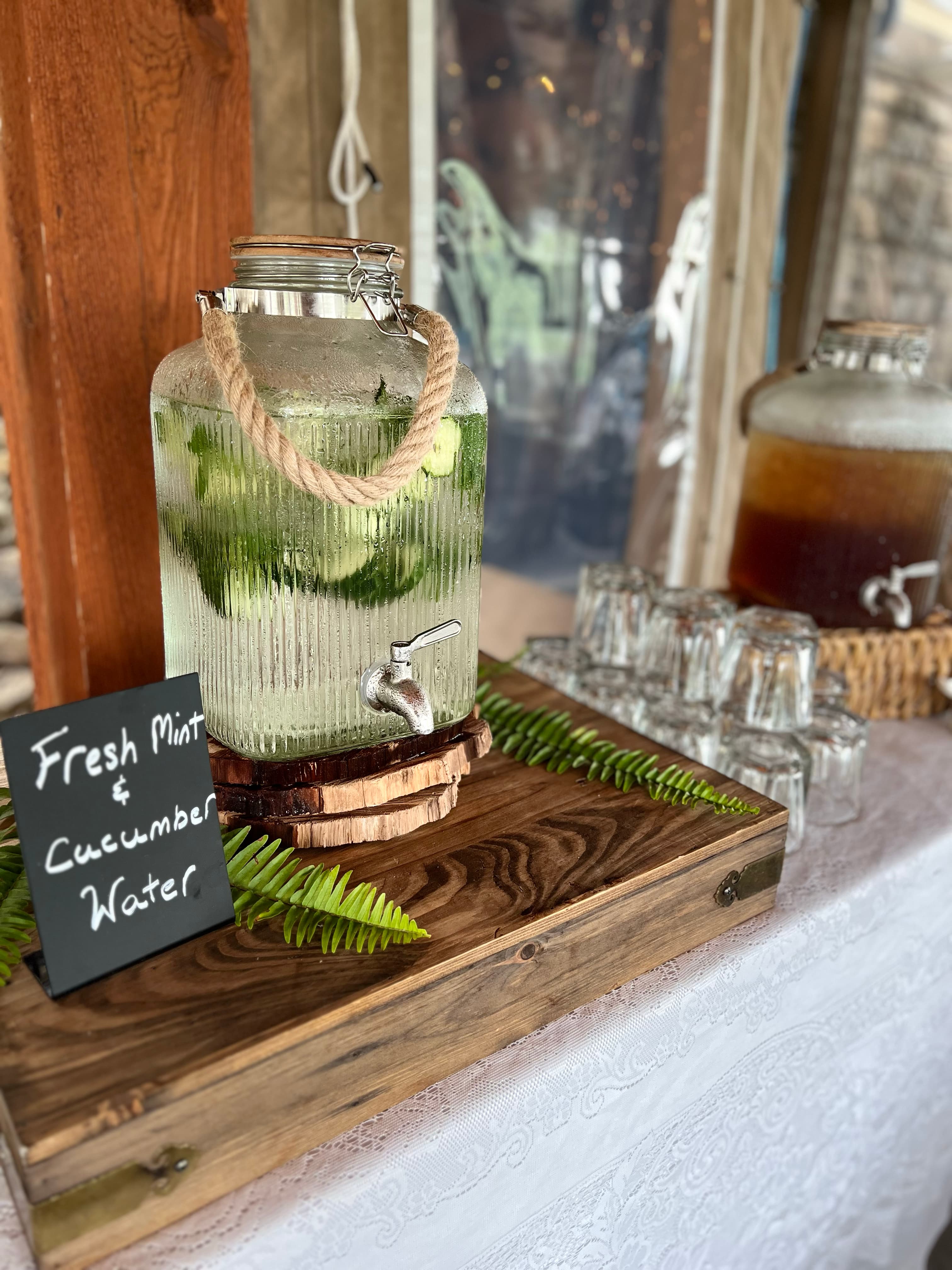 A glass jar filled with fresh mint and cucumber water, with a chalkboard sign labeling the drink.