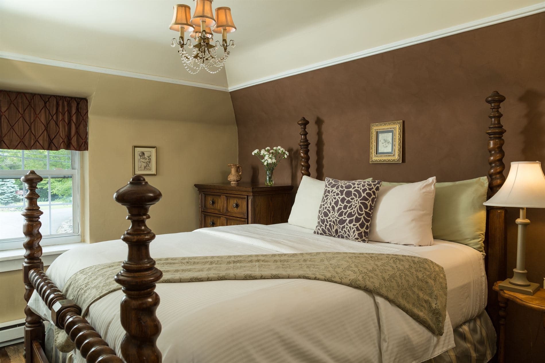 A cozy bedroom featuring a wooden four-poster bed, soft bedding, and warm-toned walls.