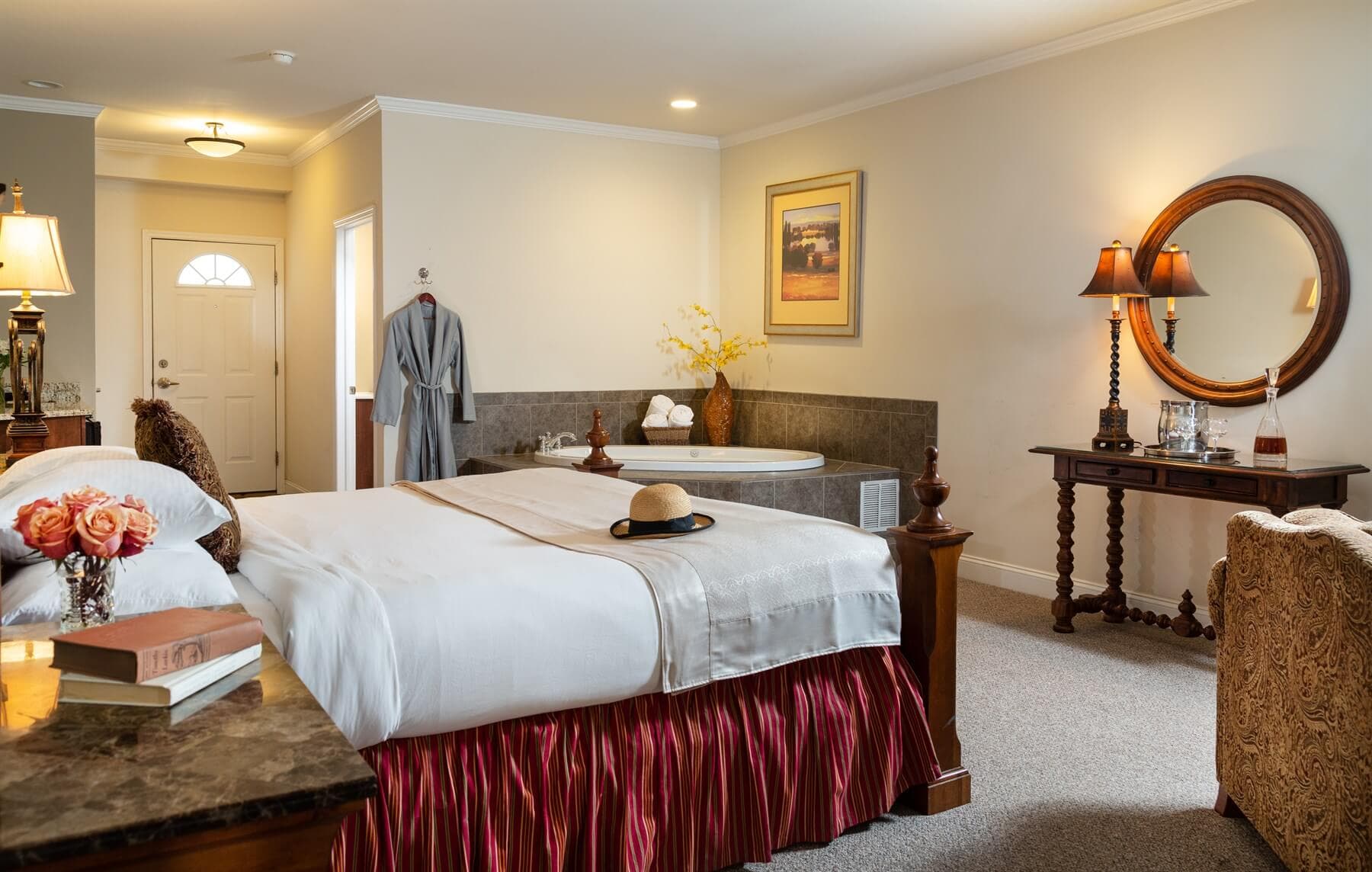 A cozy hotel room featuring a double bed, a bathtub, and elegant decor.