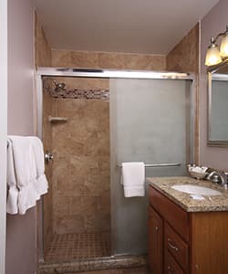 A modern bathroom featuring a glass shower, granite countertop, and neatly arranged towels.