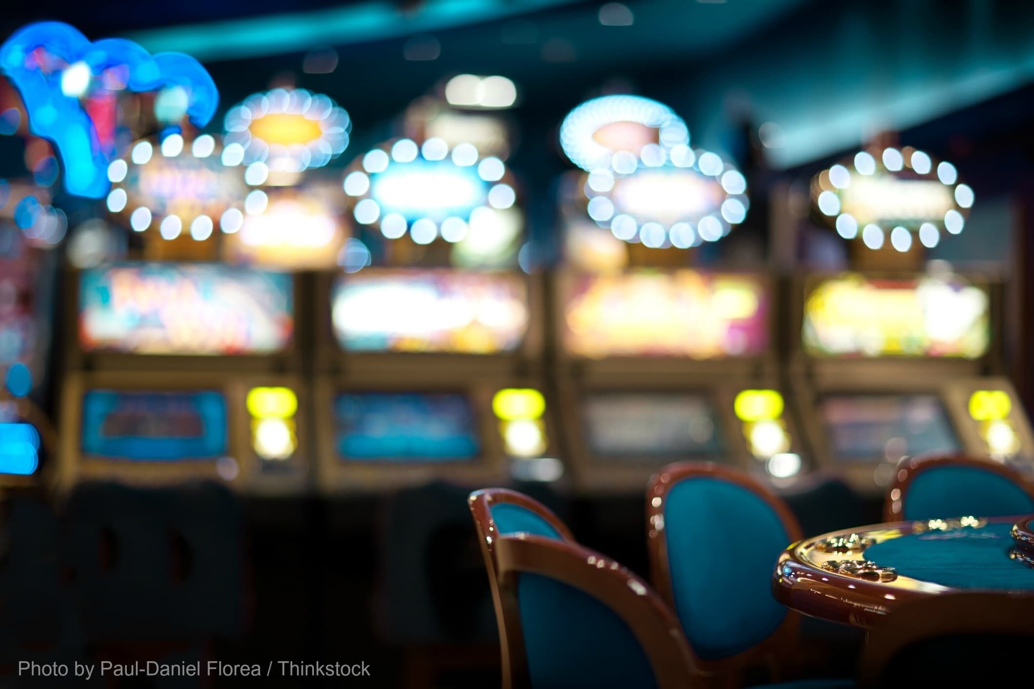 Blurry image of brightly lit slot machines in a casino setting.