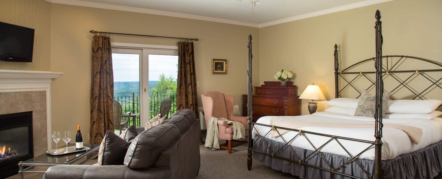 Cozy bedroom featuring a four-poster bed, a fireplace, and large windows with a view.