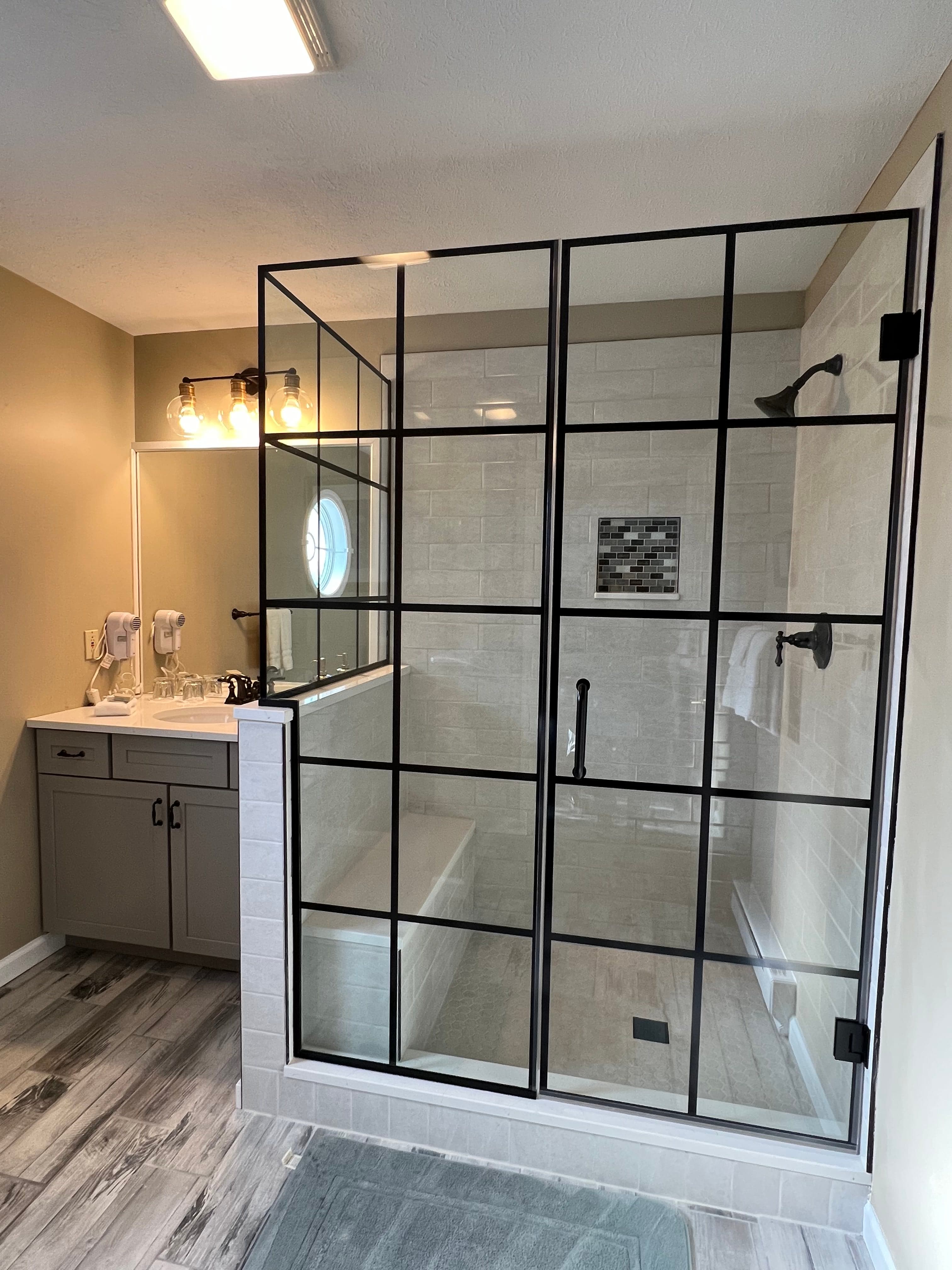 Modern bathroom featuring a walk-in shower with black grid glass doors, stylish vanity, and light fixtures.