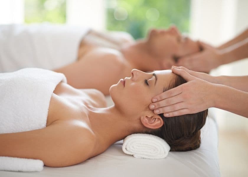 A woman receives a relaxing massage while a man lies beside her on a treatment table.