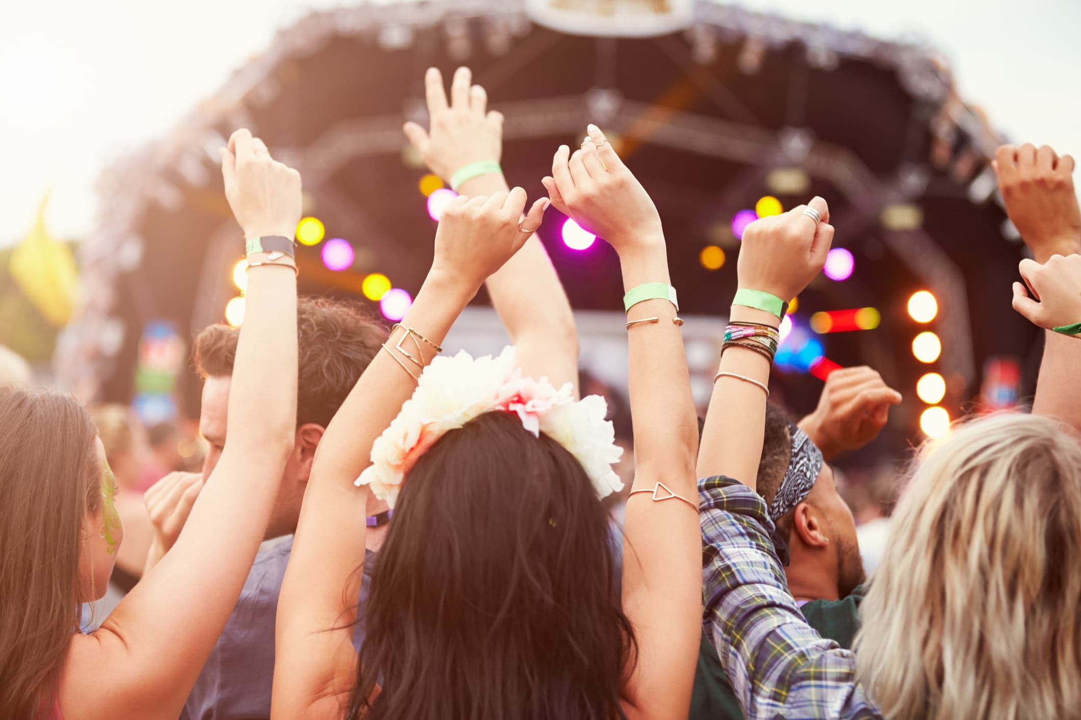 A group of people at a concert raise their arms in excitement.
