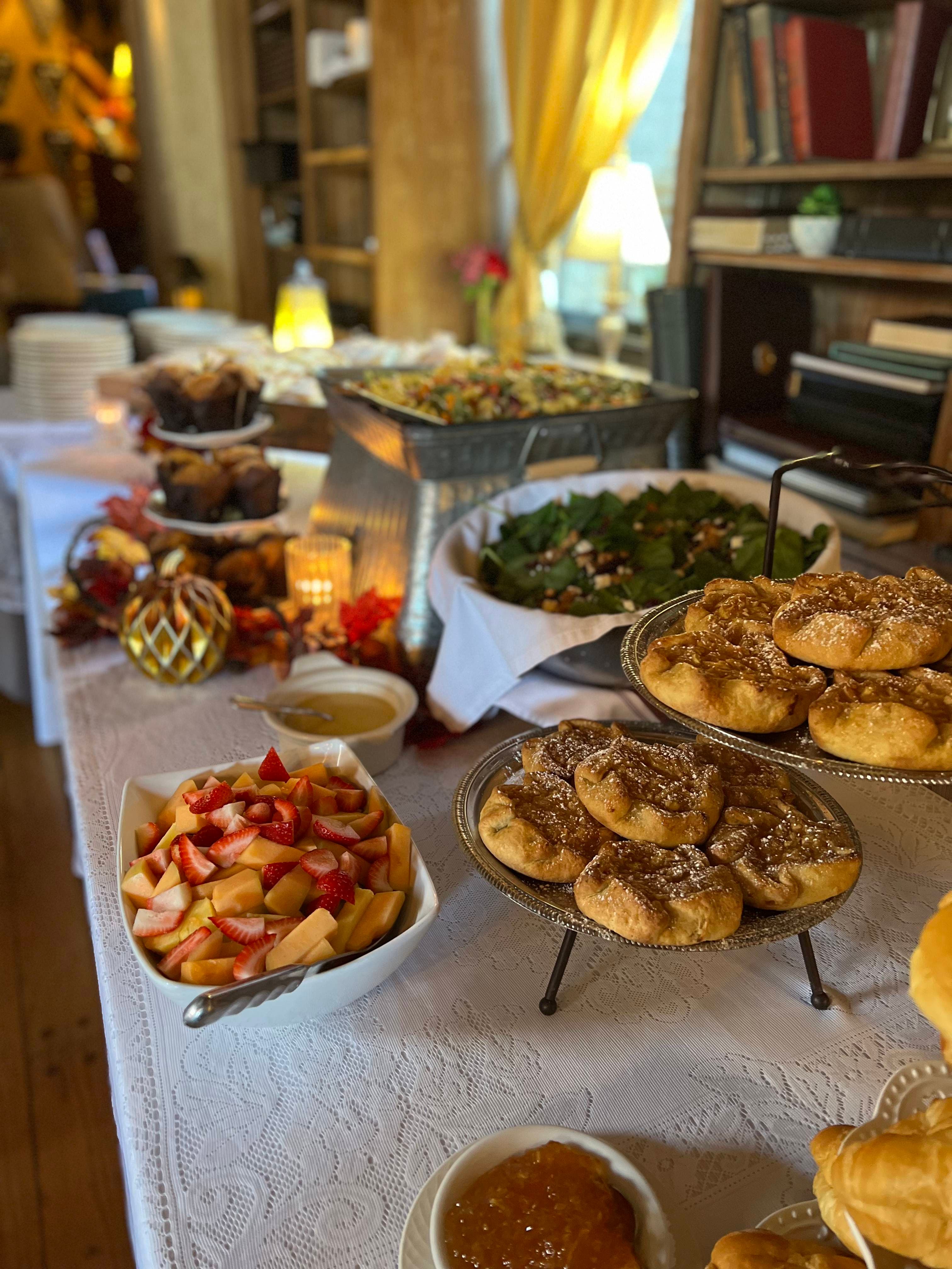 A table filled with food, including a variety of pastries, salads, fruit, and other dishes.