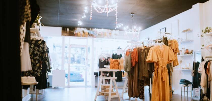 stylish boutique clothing store with dresses and accessories displayed on racks under bright decorative lighting