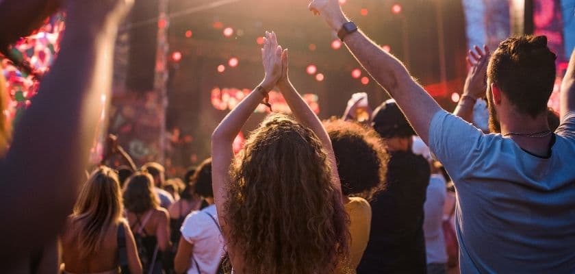 crowd of fans with arms raised at a live music concert