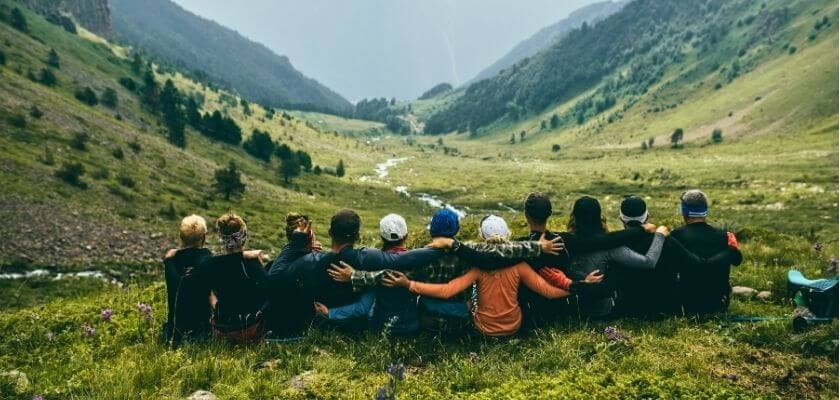 group of people sitting shoulder to shoulder looking at mountain view