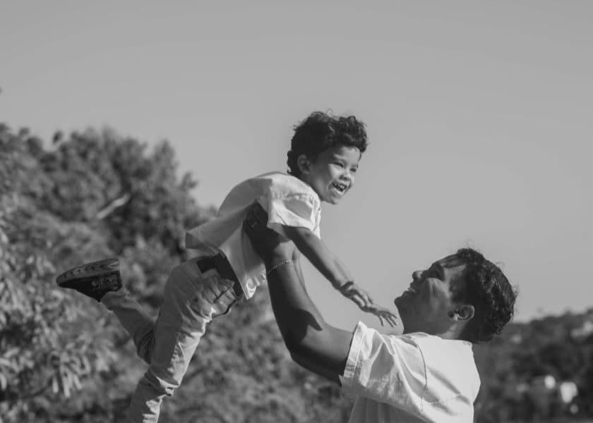 Father lifting a young child into the air while playing together outdoors in a joyful moment