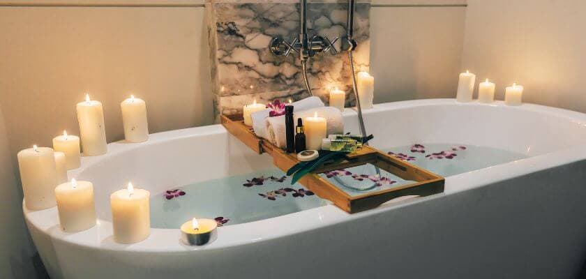 spa bath with candles, flowers, and a tray with towels